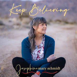 A photograph of Josephine in the desert sitting on the sand, smiling.